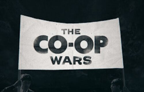 Two people holding up a sign that reads "The Co-op Wars"