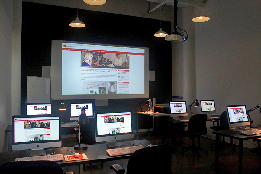 A lab with rows of iMac computers and a projector screen