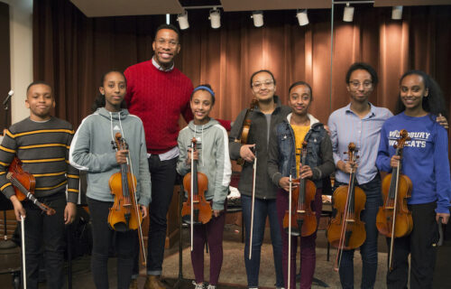 Roderick Cox standing with several teenage musicians holding violins
