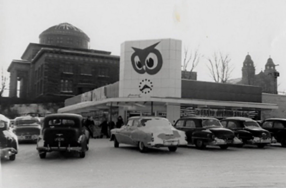 A Red Owl grocery store with several cars parked in front