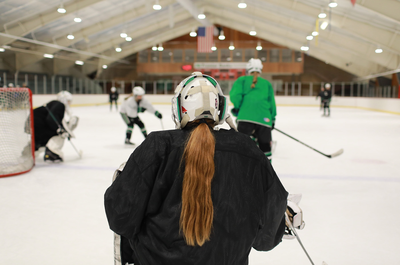 An ice rink with several young girls playing hockey